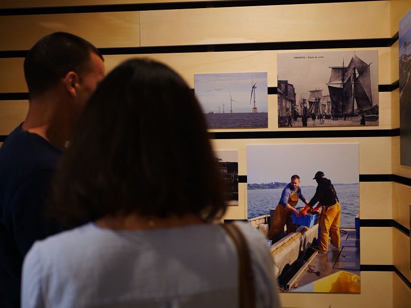 Des visiteurs regardent des photos au mur.